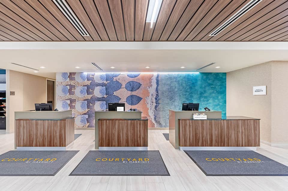 Hotel check-in desk with wood accents and coastal-themed artwork featuring turquoise tones