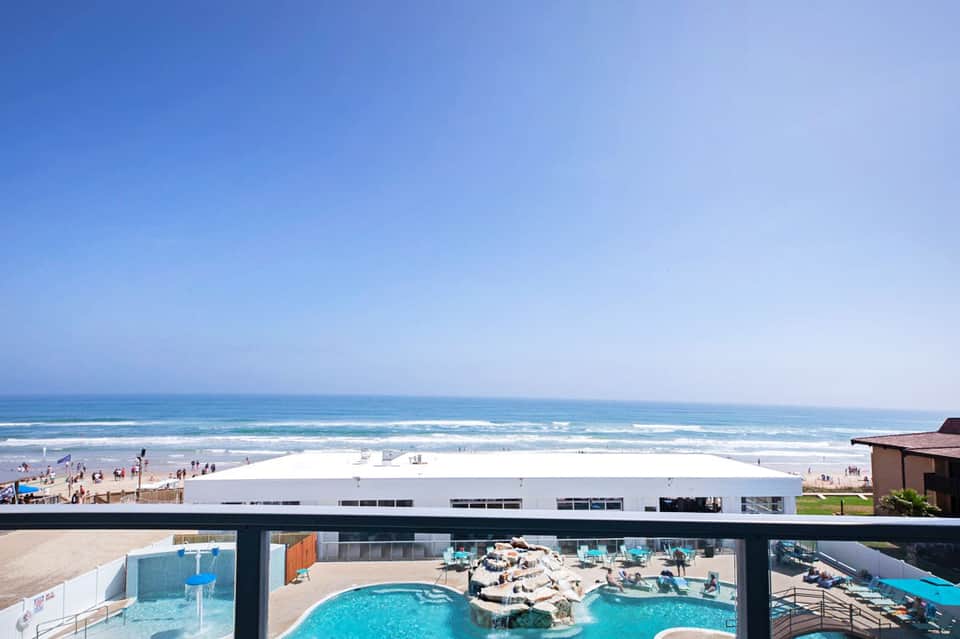 Beachfront resort pool deck with ocean view and white building structure in background
