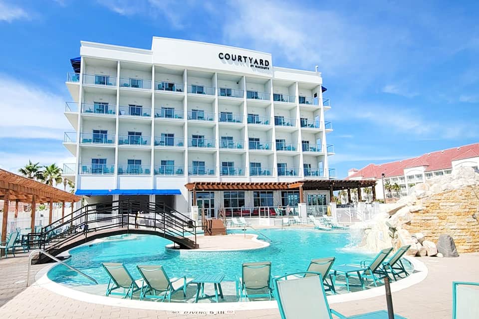 Courtyard by Marriott beachfront hotel with curved turquoise pool and lounge chairs