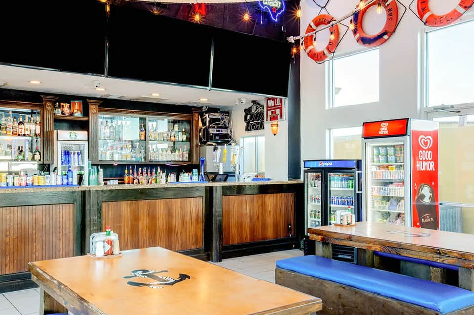 Casual bar and lounge area with wooden furnishings, neon signs, and beverage coolers