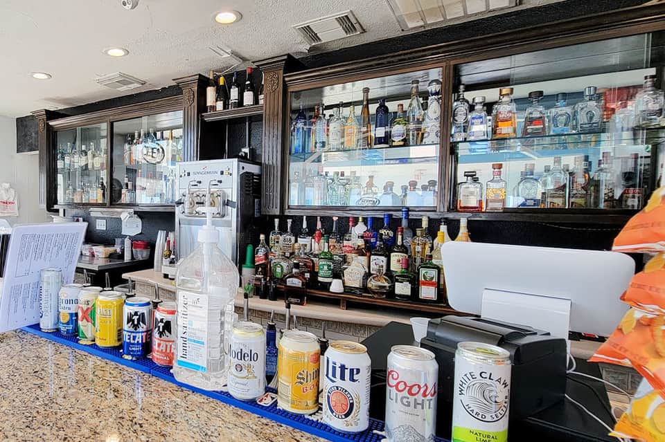 Resort bar counter displaying various beer and liquor bottles with granite countertop