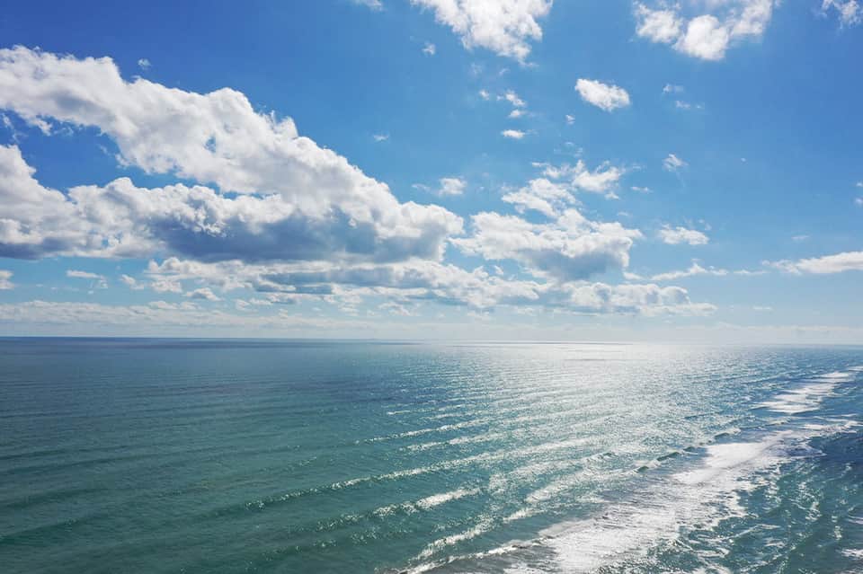Scenic ocean view with turquoise waves and white clouds under blue sky