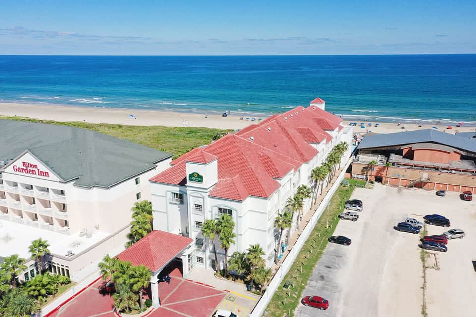 Aerial view of beachfront resort with red-roofed buildings and sandy beach