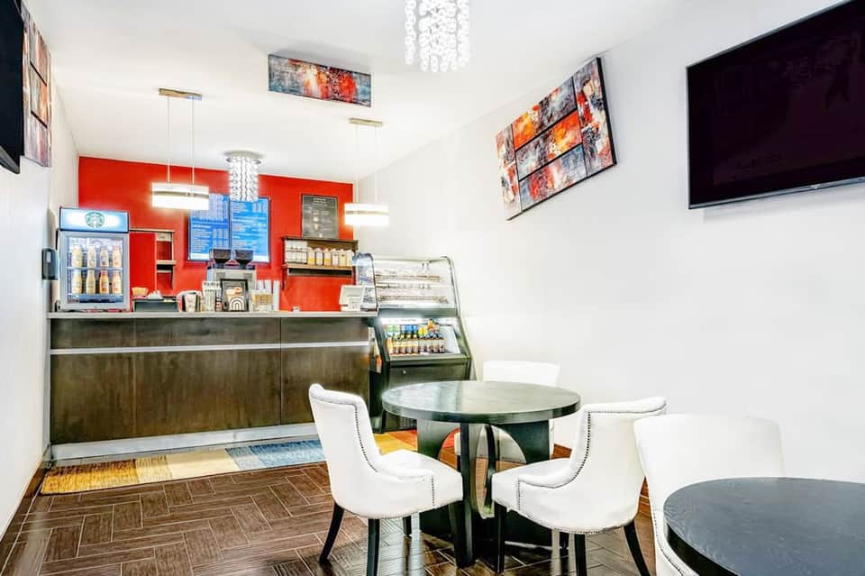Contemporary coffee shop interior with red accent wall, counter seating, and small round dining table