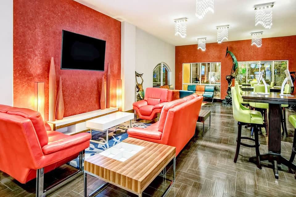Modern resort lounge area with bold red leather furniture, orange accent walls, and contemporary design