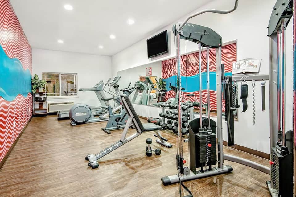 Modern fitness center with exercise equipment, cardio machines, and red chevron wall decor