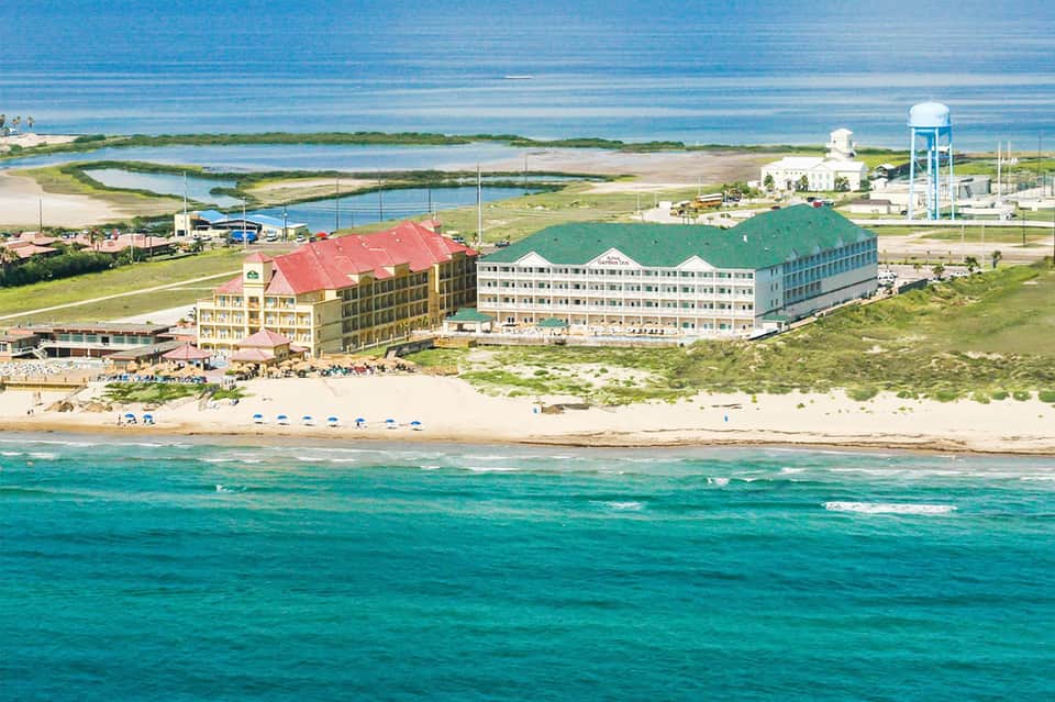 Beachfront resort with red-roofed building overlooking ocean and marsh landscape