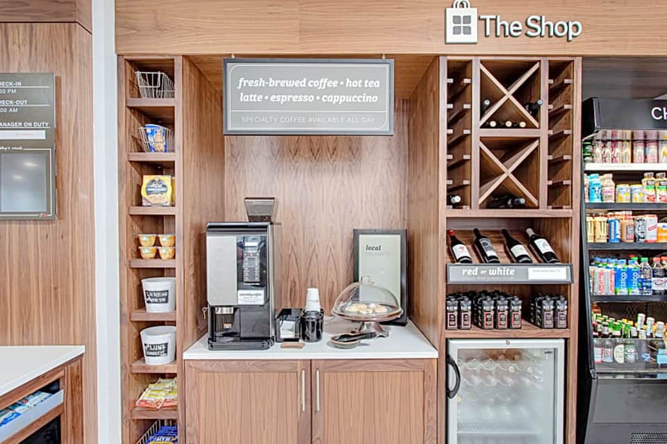 The Shop coffee bar with wooden cabinetry, coffee machine, and retail shelves