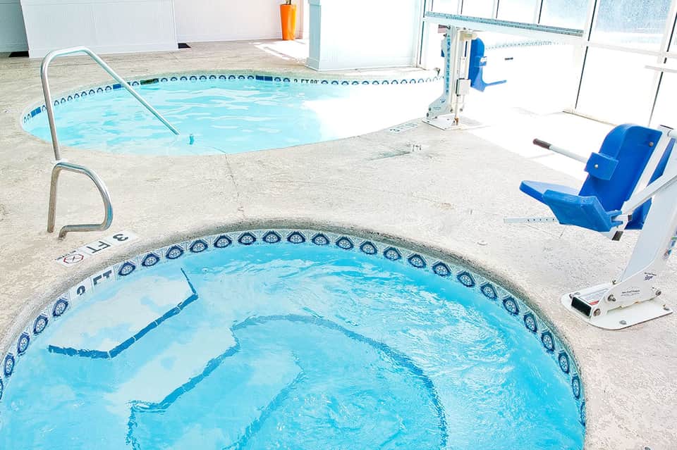 Indoor hot tub and swimming pool facility with white walls and blue chairs