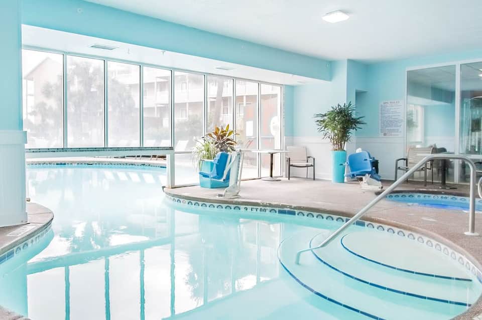 Indoor spa pool area with turquoise water, large windows, and modern architectural design