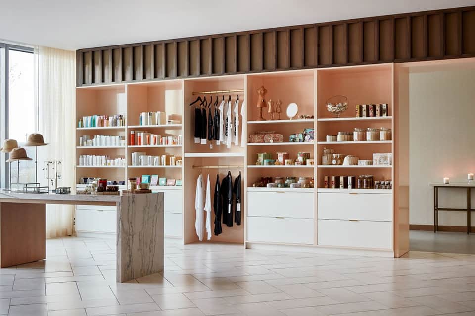 Luxury retail boutique interior with peach shelving, white cabinetry, and brown wood ceiling details