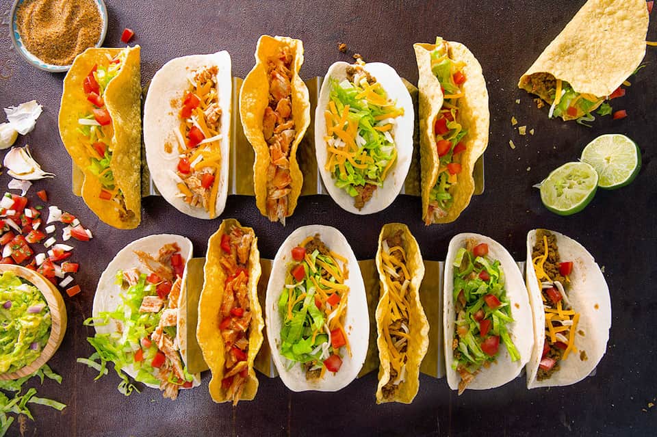 Assorted tacos with various fillings, lime wedges, and condiments