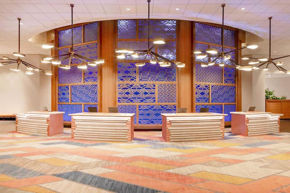 Modern hotel lobby with curved wooden reception desks and blue patterned glass wall