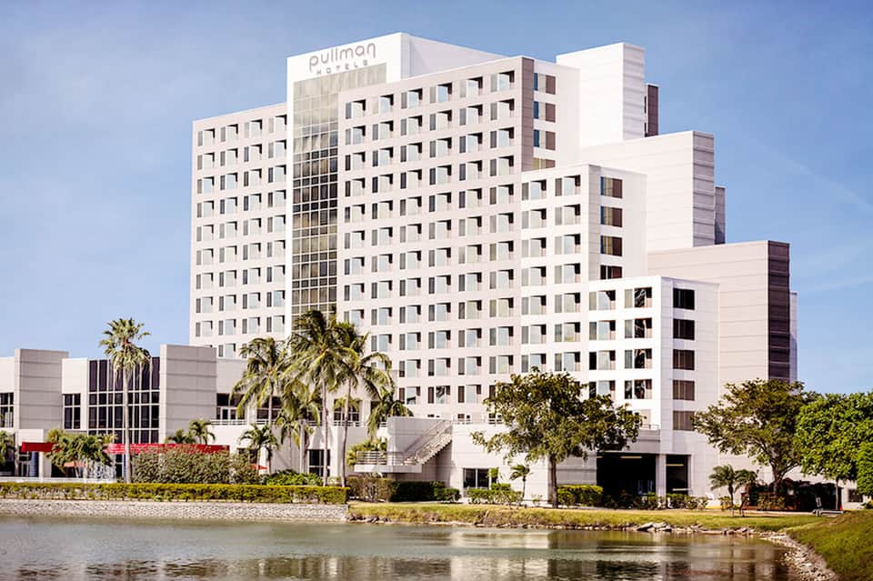 Pullman hotel, modern white multi-story building beside a river with palm trees