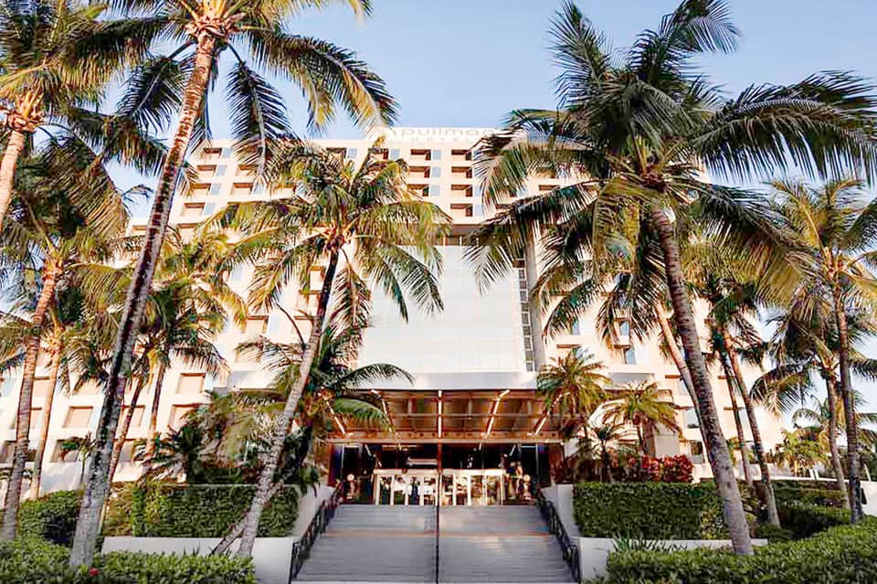 Modern hotel building with palm trees lining the entrance and contemporary architecture