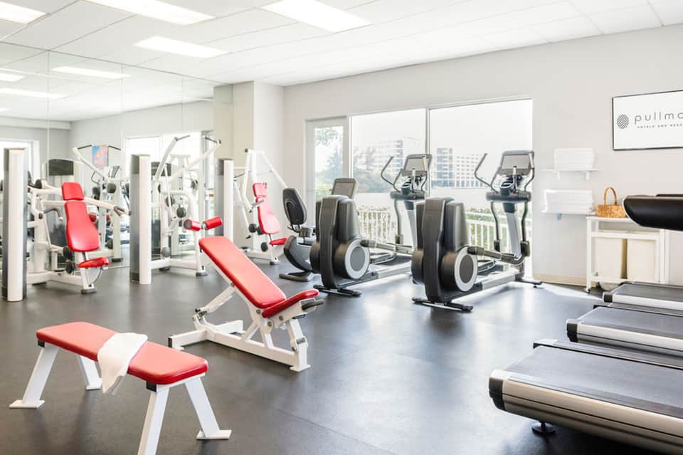 Modern fitness center with cardio equipment, weight machines, and red workout benches