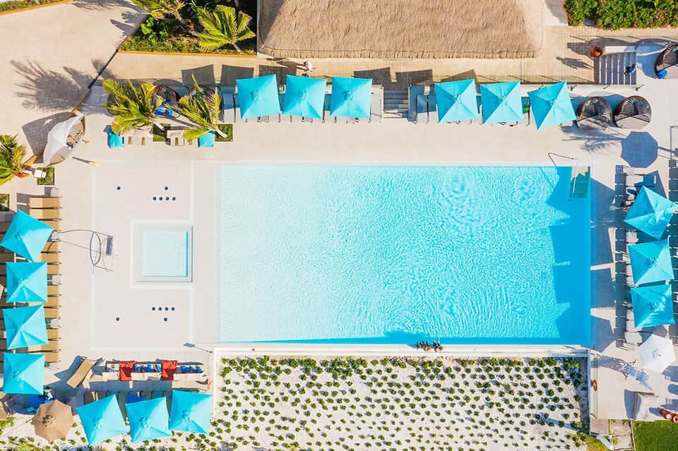 Aerial view of resort pool surrounded by blue umbrellas and lounge chairs