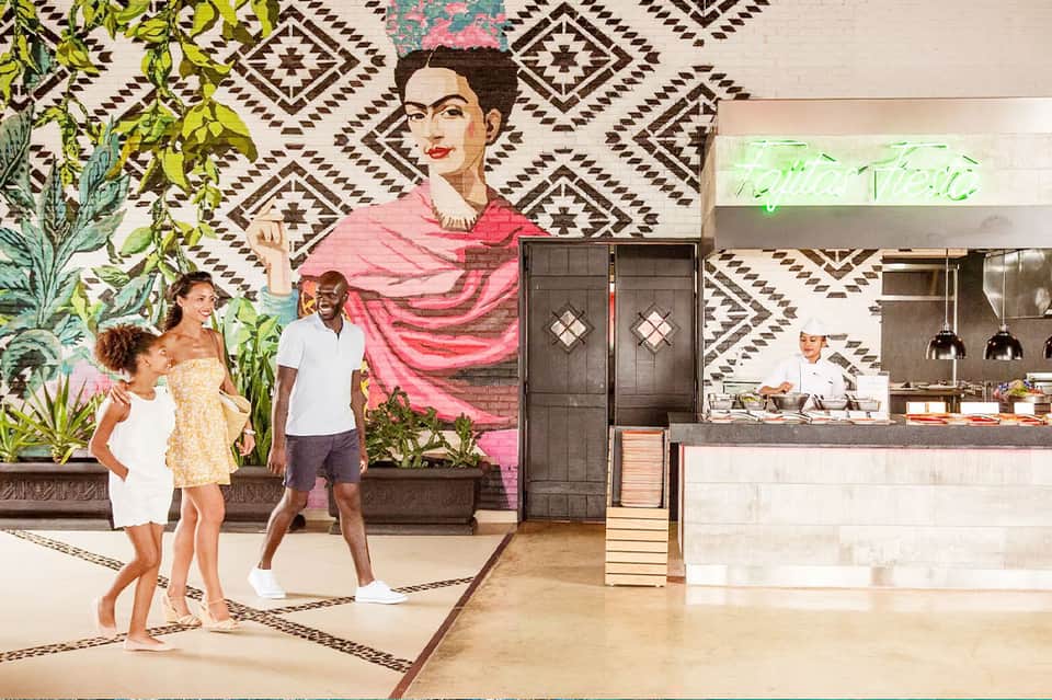 Contemporary restaurant interior with artistic mural and family dining by open kitchen