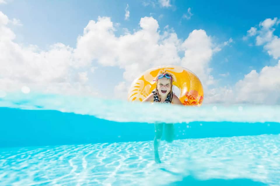 Child in yellow float ring enjoying crystal clear turquoise ocean water