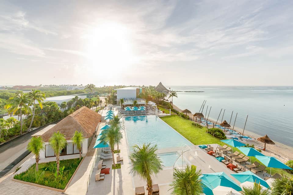 Aerial view of luxury beachfront resort with infinity pool, palm trees, and turquoise ocean