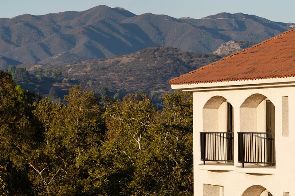 Spanish colonial-style building with arched windows overlooking forested mountains