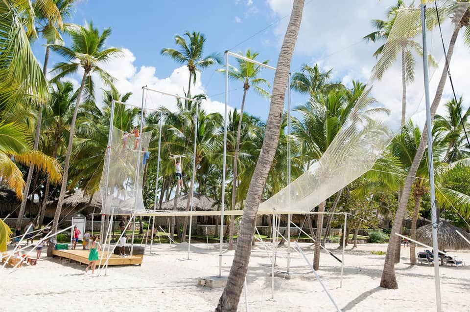 Beach volleyball court surrounded by palm trees on sandy resort grounds