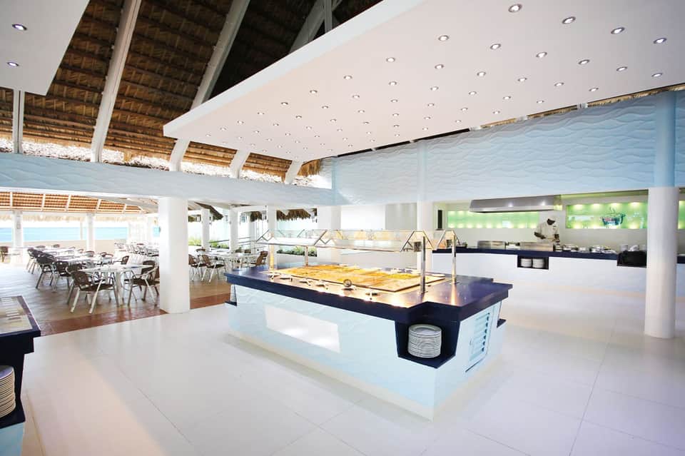 Modern hotel restaurant with open kitchen, buffet counter, white ceiling, and ocean views