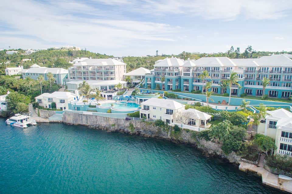 Aerial view of turquoise beachfront resort with colorful buildings and swimming pools