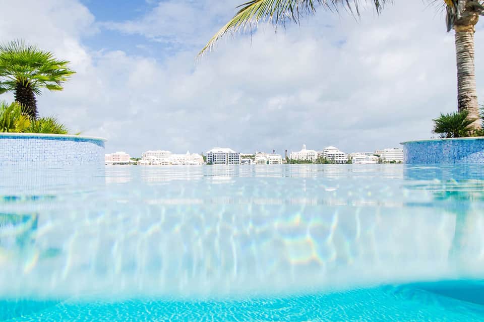Infinity pool with palm trees overlooking beachfront buildings and turquoise water