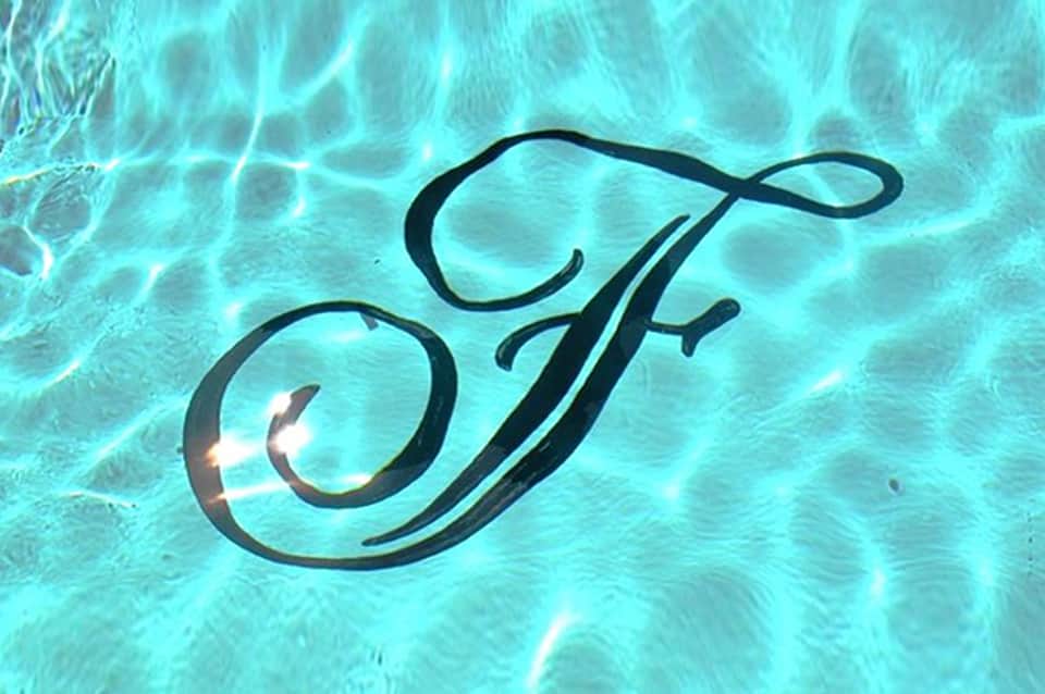 Elegant cursive 'F' logo reflected in clear turquoise pool water