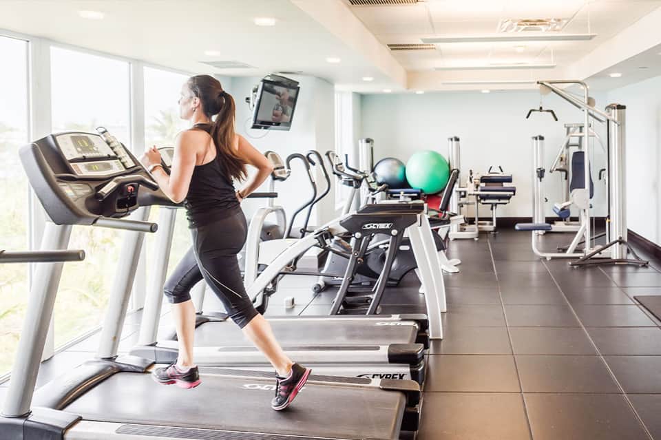 Woman running on treadmill in bright fitness center with cardio equipment