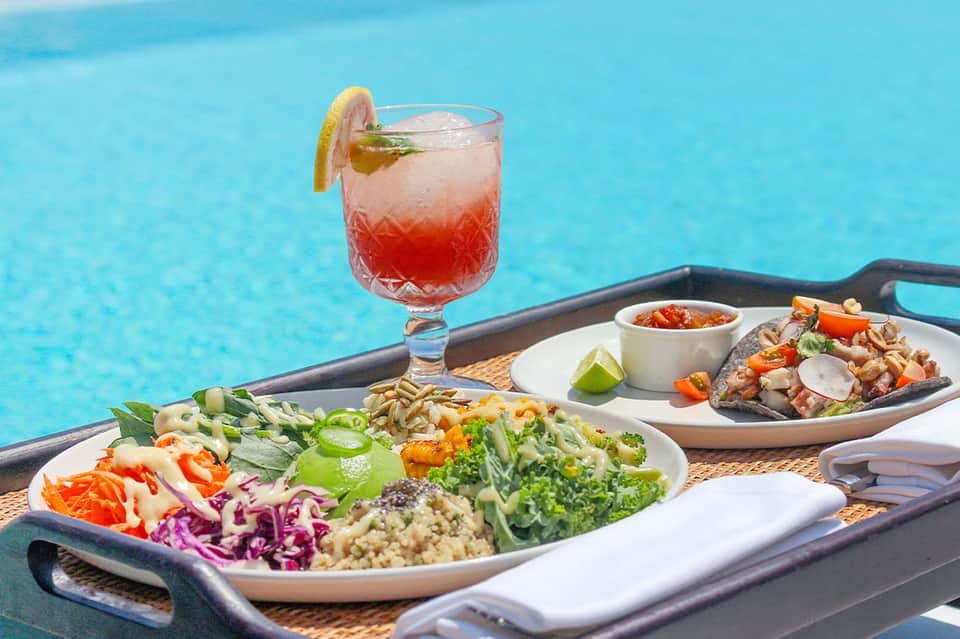 Poolside cocktail and appetizer plates with colorful salad and grilled items