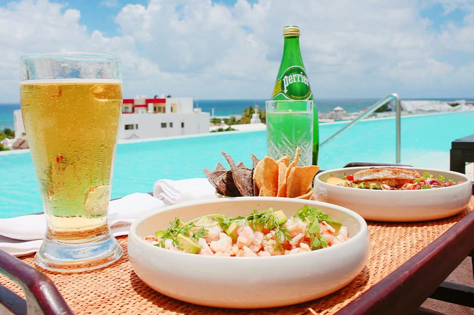 Poolside dining with ceviche, bread, Perrier bottle, and ocean view in background
