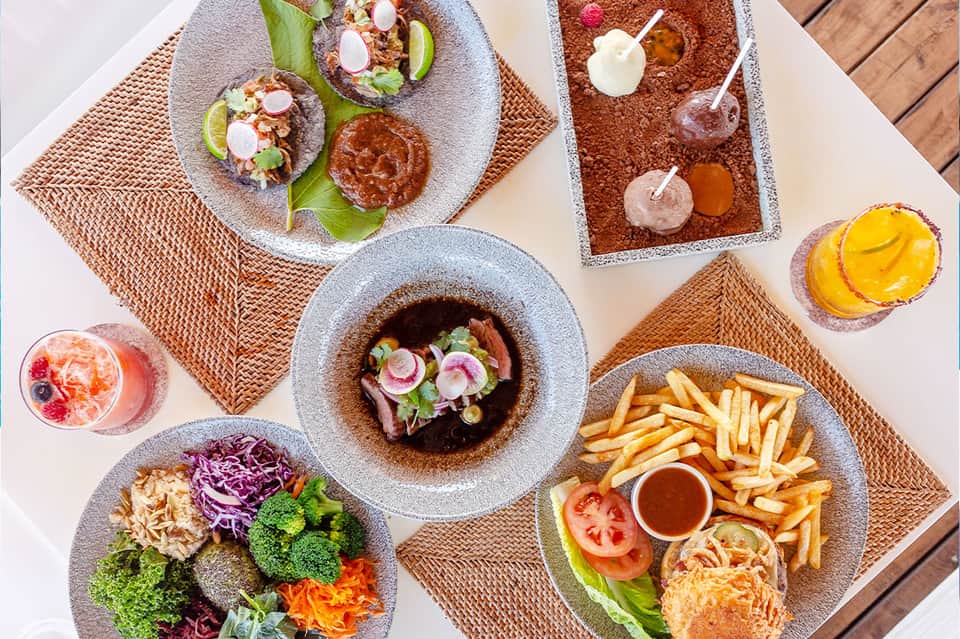 Overhead view of upscale dining spread with tacos, appetizers, and colorful tropical drinks