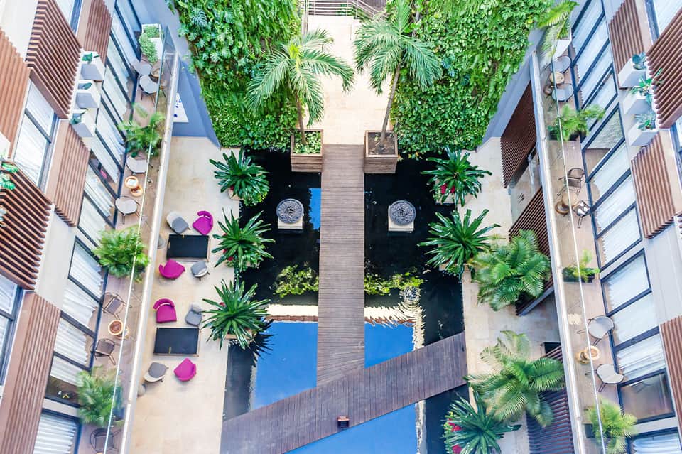 Aerial view of a modern courtyard with pools, tropical plants, and pink umbrellas
