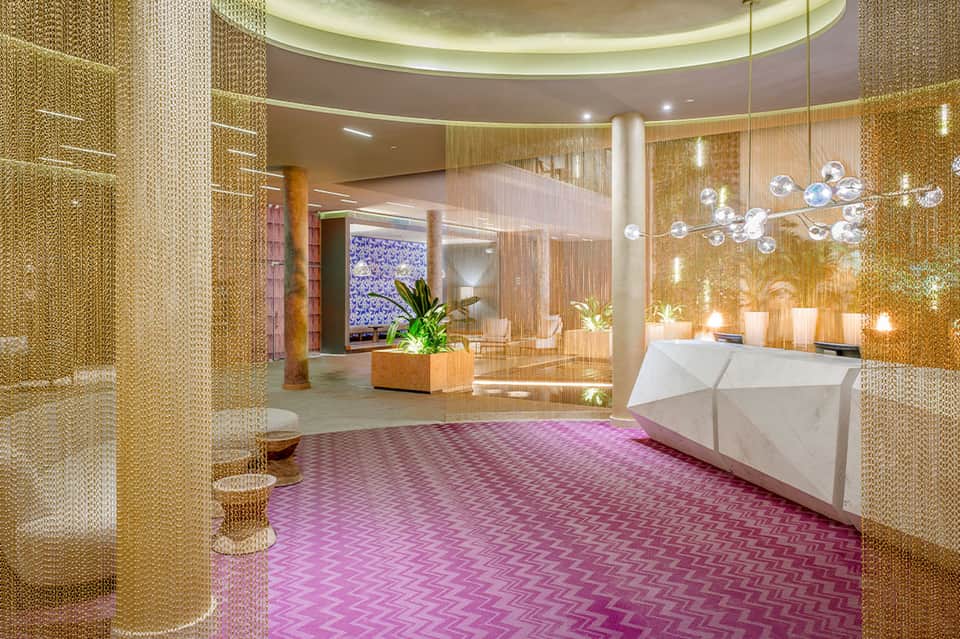 Luxurious spa lobby with golden metallic curtains, bubble chandelier, and modern white reception desk