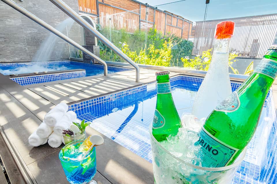 Rooftop pool area with green beer bottles, cocktails, and lounge chairs