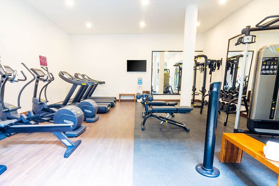 Modern fitness center with blue exercise bikes, treadmills, and weight training equipment