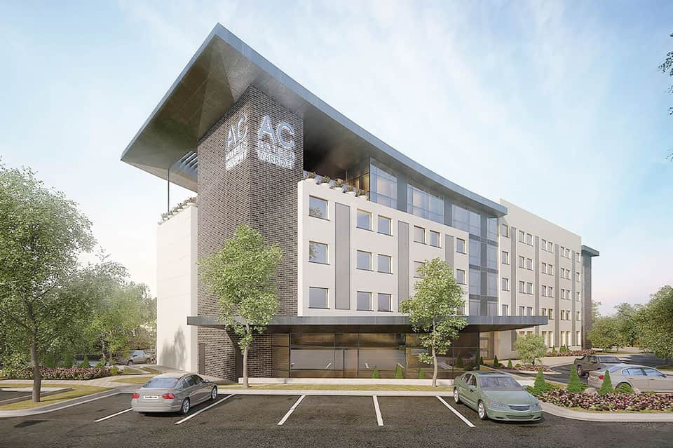 Modern multi-story hotel building with brick and cream facade, ground floor retail space, parking lot