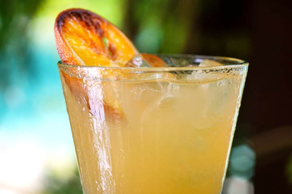 Refreshing citrus cocktail with orange slice garnish and ice in clear glass outdoors