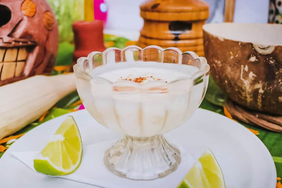Margarita cocktail in a decorative glass with lime wedges and cinnamon garnish