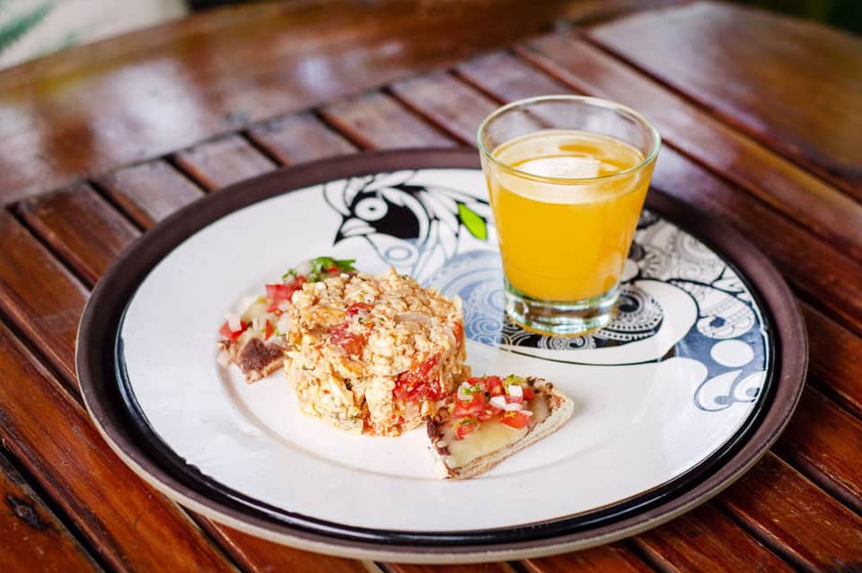 Plate with egg scramble and toast next to glass of orange juice on wooden table