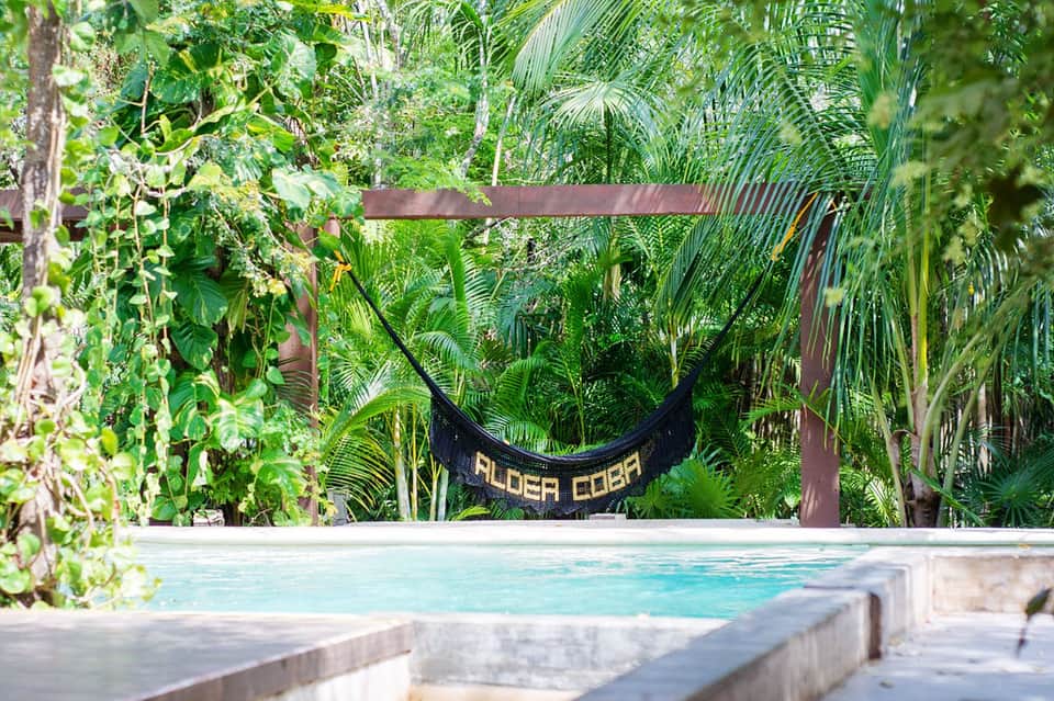 Turquoise pool surrounded by lush tropical vegetation and hammock