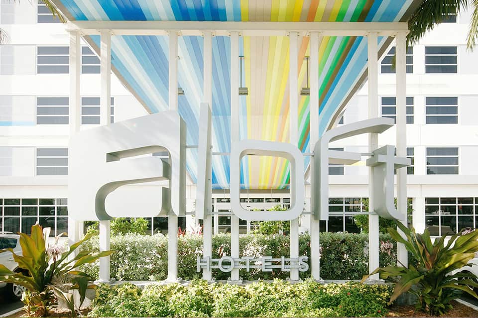 Colorful striped pergola canopy over modern resort courtyard with landscaping
