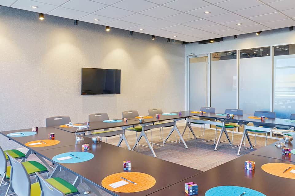 Modern conference room with long tables, colorful placemats, and oceanfront windows