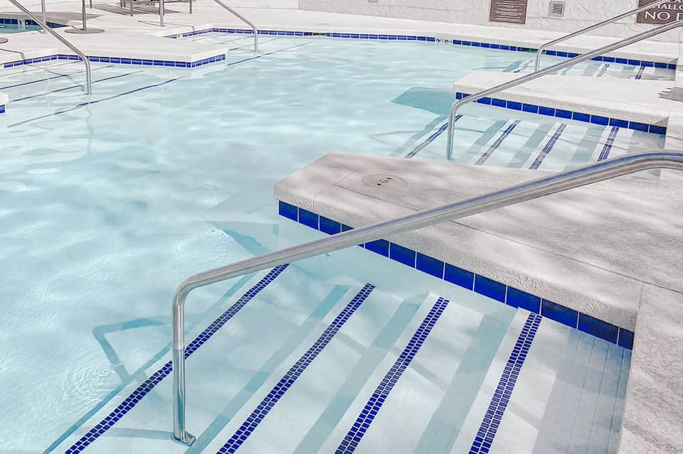 Indoor lap pool with lane dividers and white towels on deck chairs
