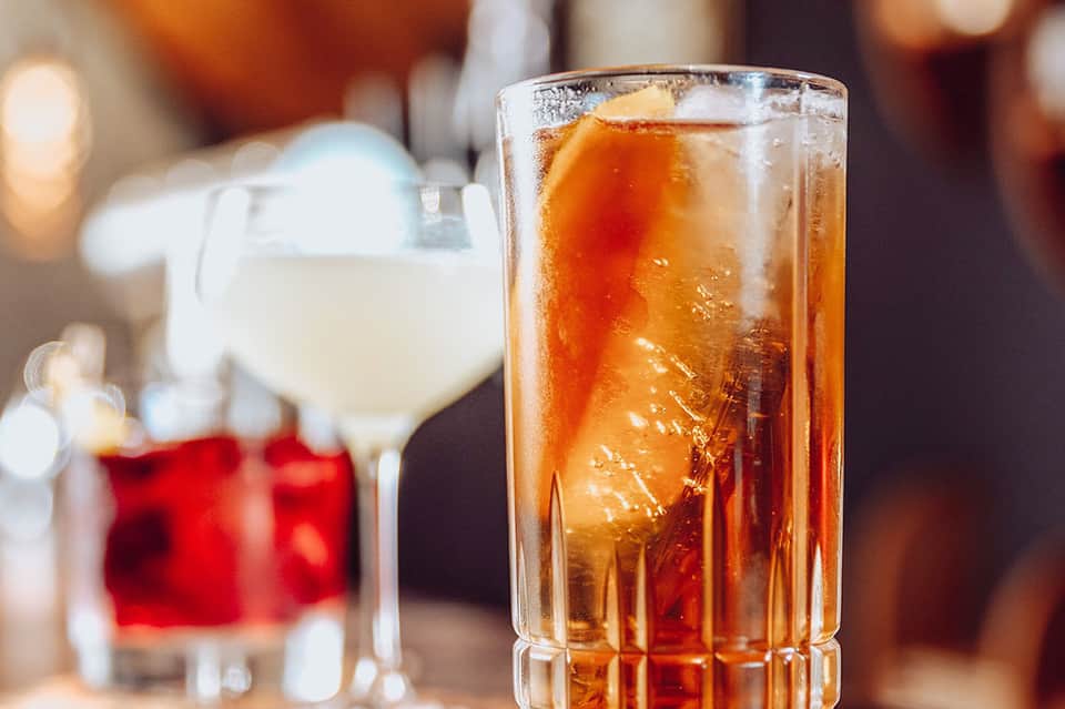 Cocktails with amber and clear drinks on a bar counter with warm lighting