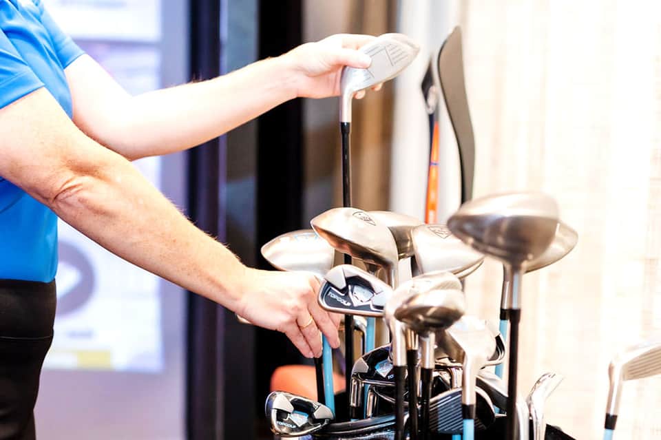 Person selecting golf club from bag at indoor golf facility