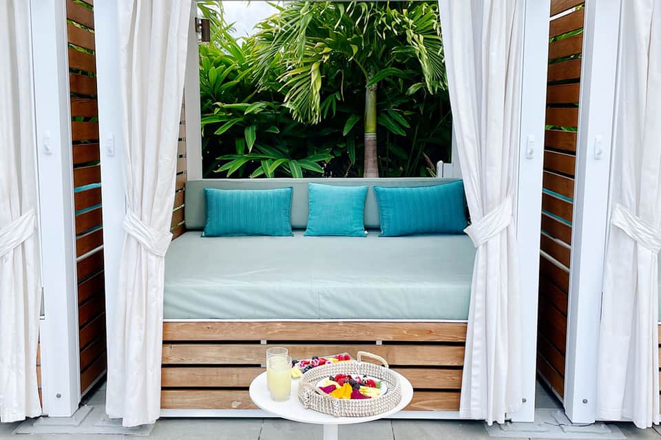 Luxurious daybed with turquoise pillows and white curtains in tropical setting