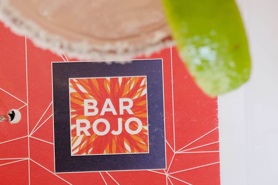 Bar Rojo cocktail menu with red geometric design and lime garnish closeup